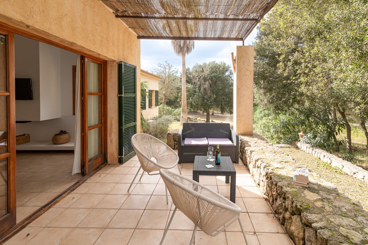 A patio with chairs and a table with a bottle of wine on it