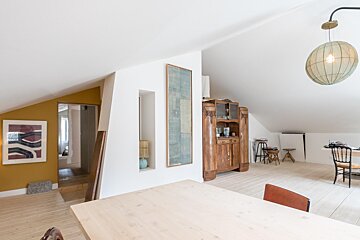 A dining room with a table and chairs and a mirror on the wall