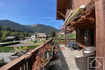 A balcony with a table and chairs and mountains in the background
