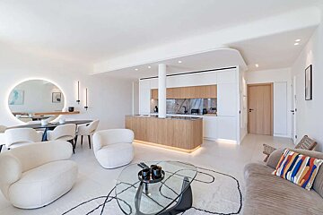 A living room with white furniture and a round mirror