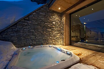 A hot tub is sitting in front of a stone wall