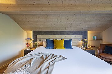 A bed with blue and yellow pillows and a blanket on it