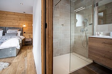 A bathroom with a walk in shower next to a bedroom
