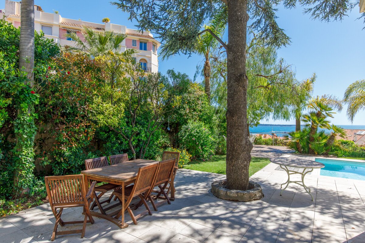 A patio with a table and chairs next to a pool
