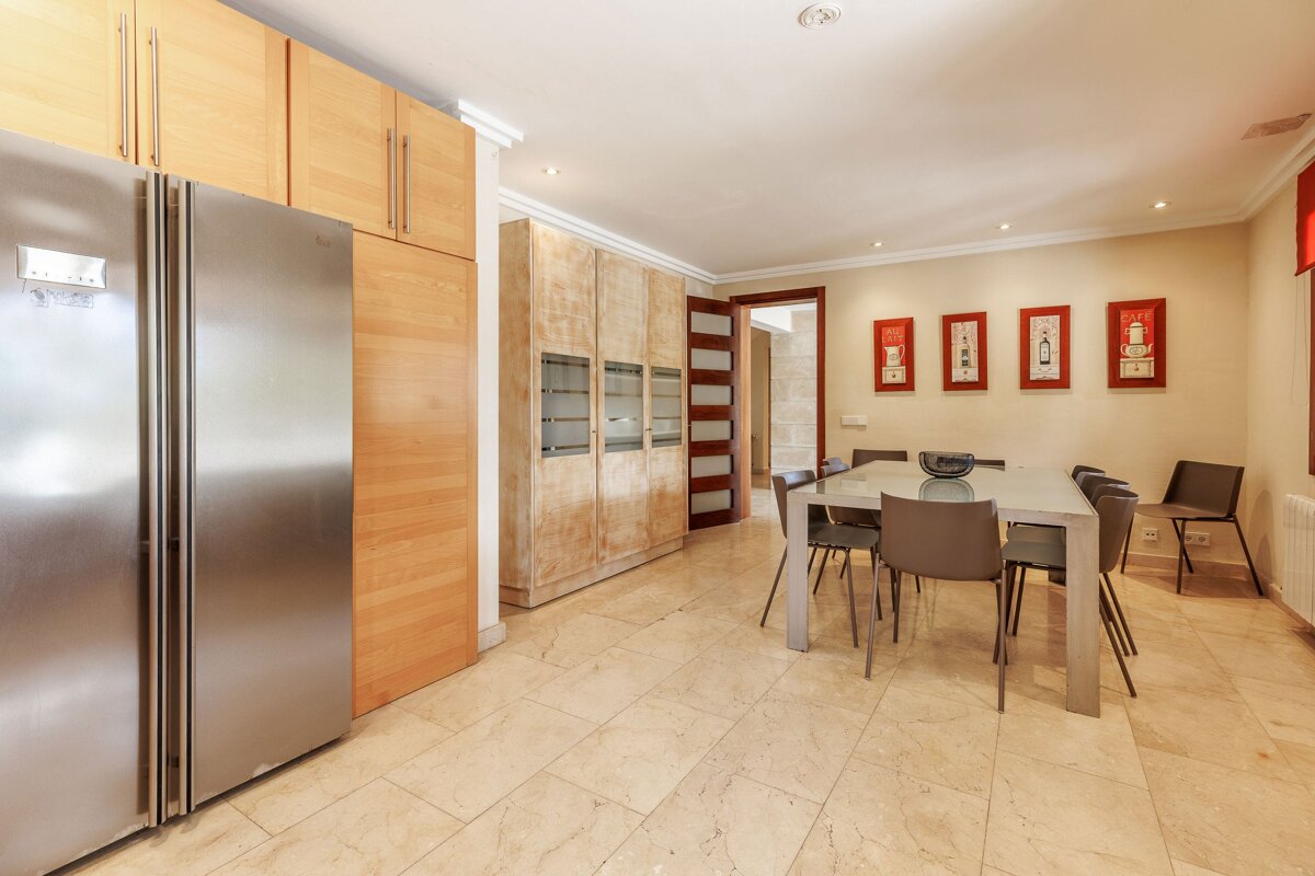 A kitchen with a stainless steel refrigerator and a dining table