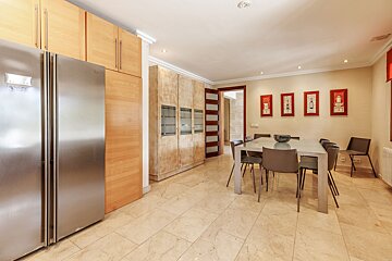 A kitchen with a stainless steel refrigerator and a dining table