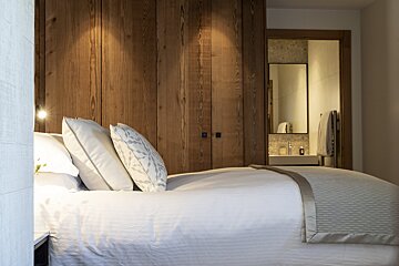 A bedroom with a bed and a bathroom in the background
