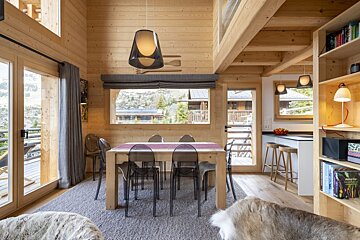 A wooden house with a dining table and chairs