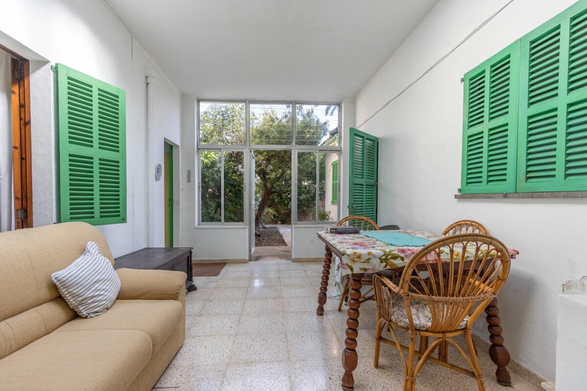 A living room with a table and chairs and green shutters