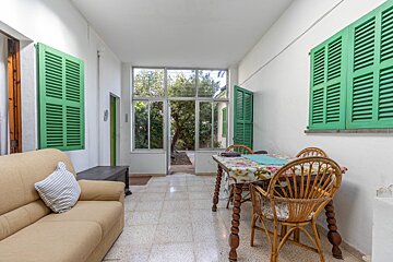 A living room with a table and chairs and green shutters