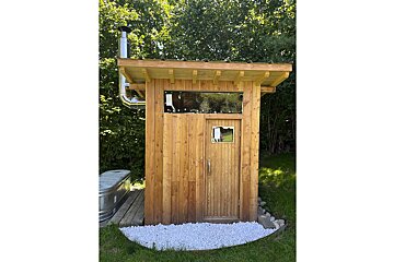 A small wooden shed with a chimney on top of it
