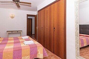 A bedroom with a ceiling fan and a large mirror