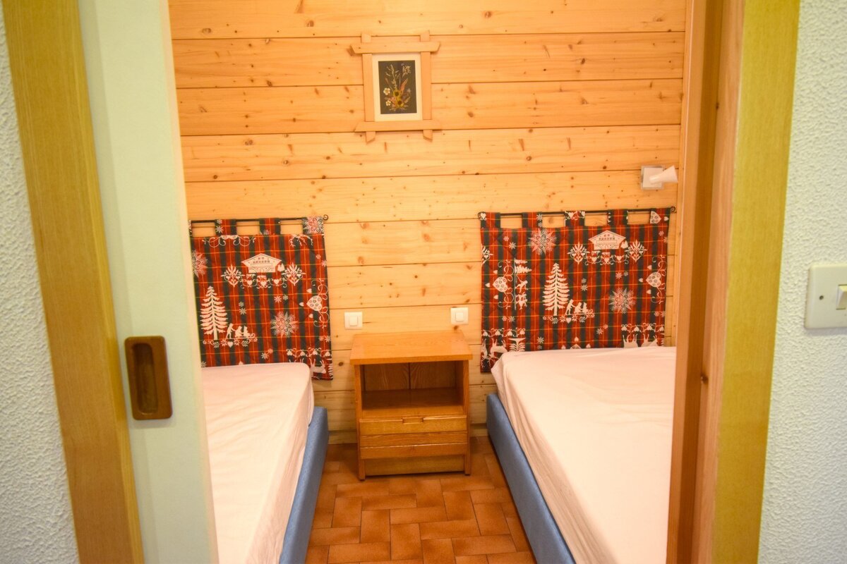 A bedroom with two beds and a nightstand