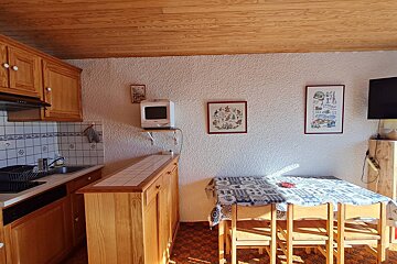 A kitchen with a table and chairs and a tv on the wall