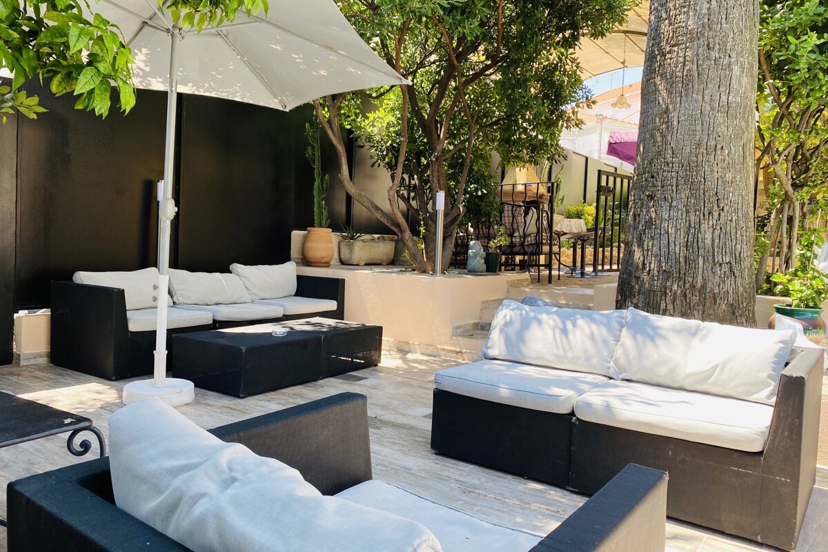 A patio area with a couch and chairs under an umbrella