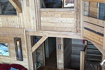 A wooden house with a red couch and stairs