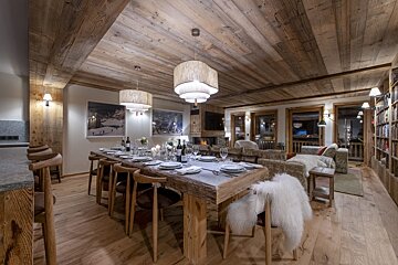 A dining room with a long wooden table and chairs