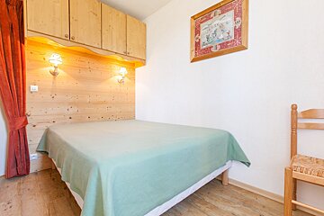 A small bedroom with a bed and a chair