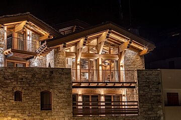 A large stone building with wooden beams is lit up at night