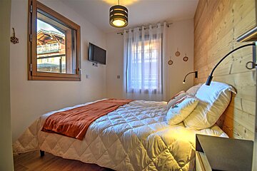 A bedroom with a bed and a television on the wall
