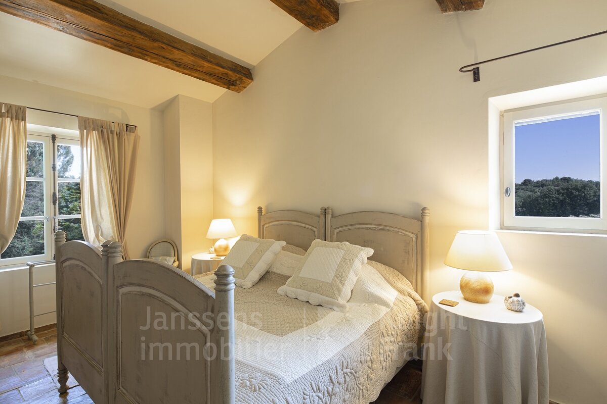 A bedroom with a bed and two lamps and the words janssens immobilier on the wall