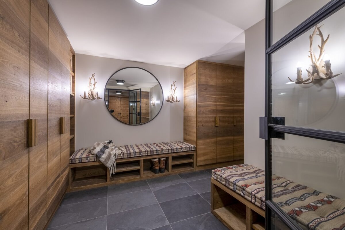 A hallway with a bench and a round mirror