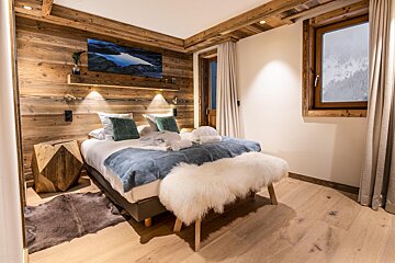 A bedroom with a painting on the wall above the bed