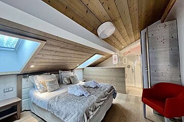 A bedroom with a large bed and a red chair