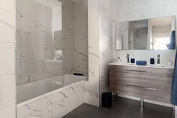 A bathroom with marble tiles and a bathtub