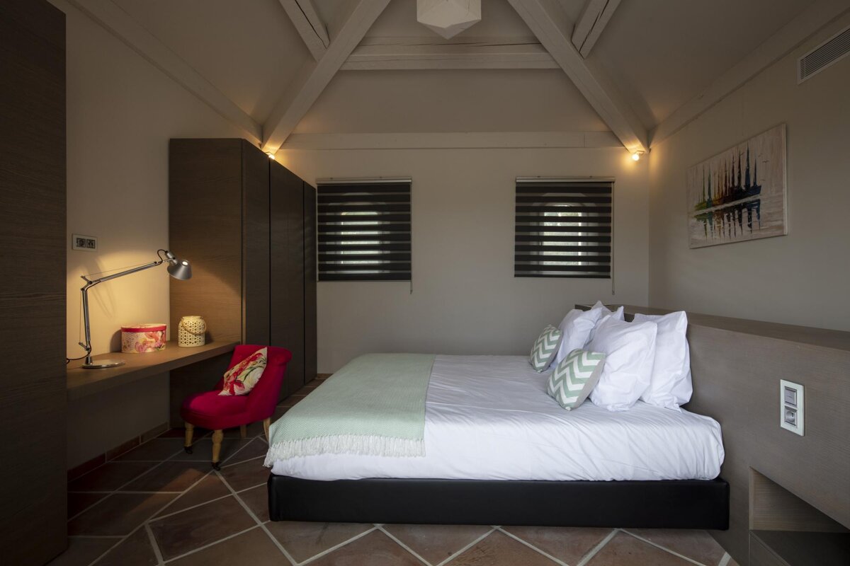A bedroom with a bed a desk and a lamp
