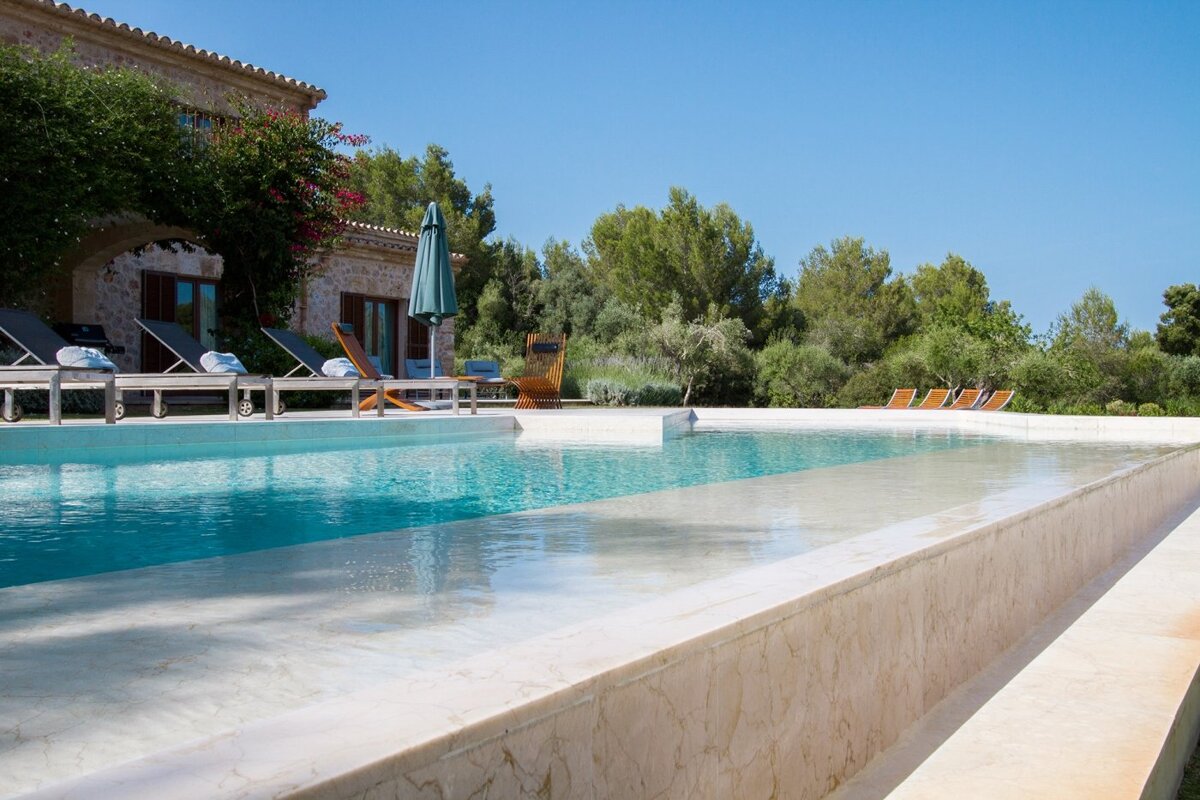 A large swimming pool surrounded by chairs and umbrellas