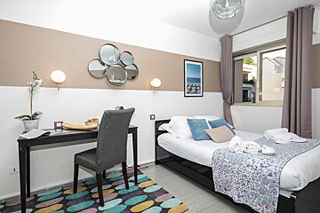 A bedroom with a bed a desk and a picture on the wall