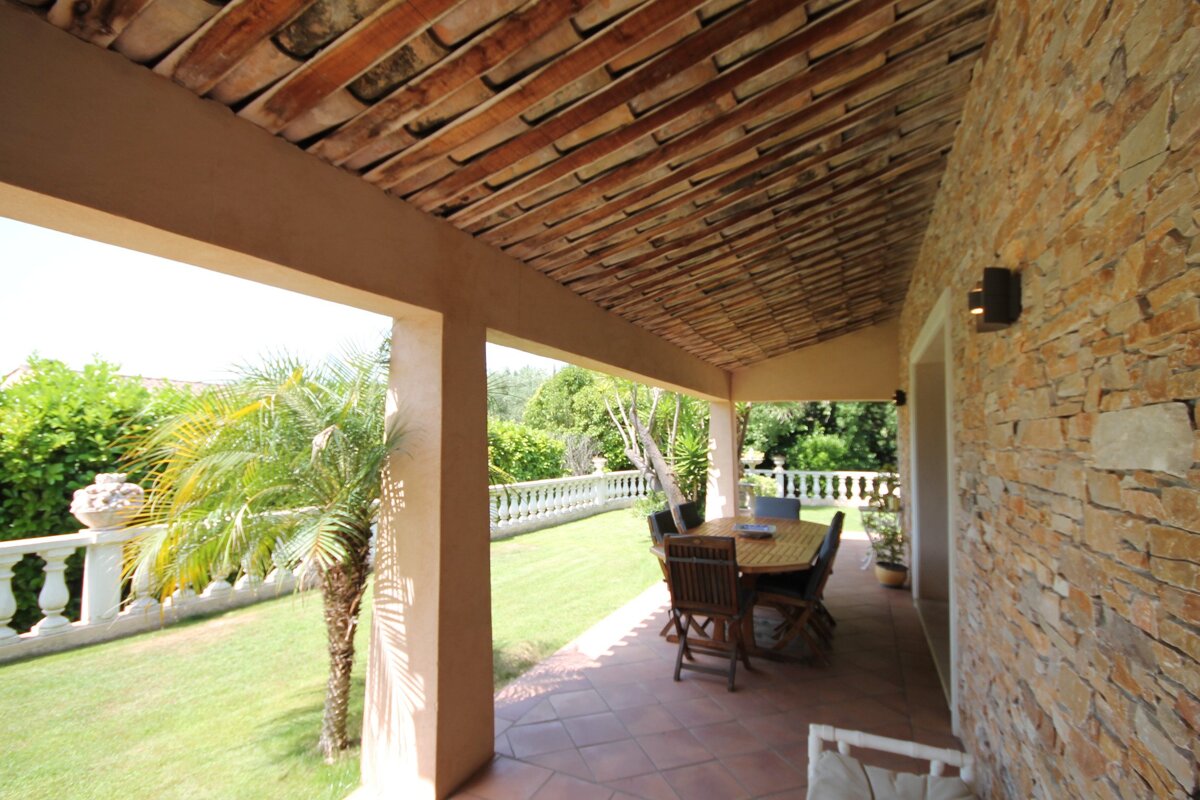 A patio with a table and chairs under a roof