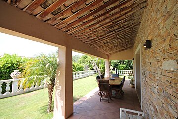 A patio with a table and chairs under a roof