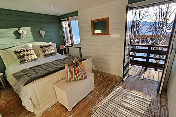A bedroom with a large bed and a balcony