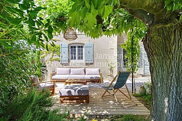 A patio with a couch and chairs under a tree with the word janssens in the corner