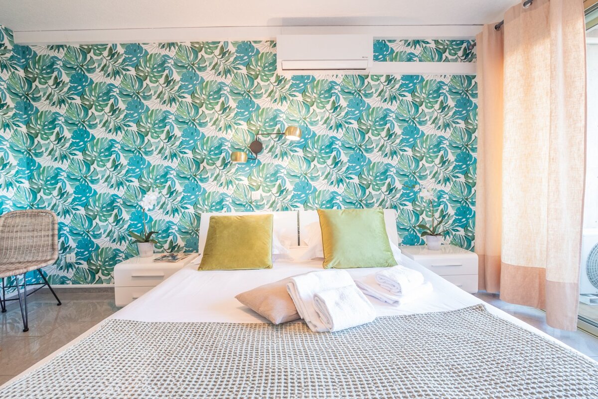 A bedroom with a tropical wallpaper on the wall