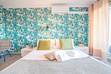 A bedroom with a tropical wallpaper on the wall