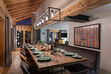 A dining room table with plates and glasses and a bottle of wine on it