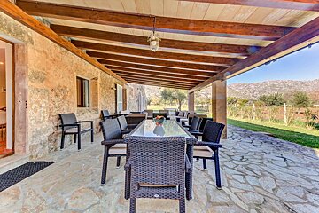 A patio with a table and chairs under a wooden roof
