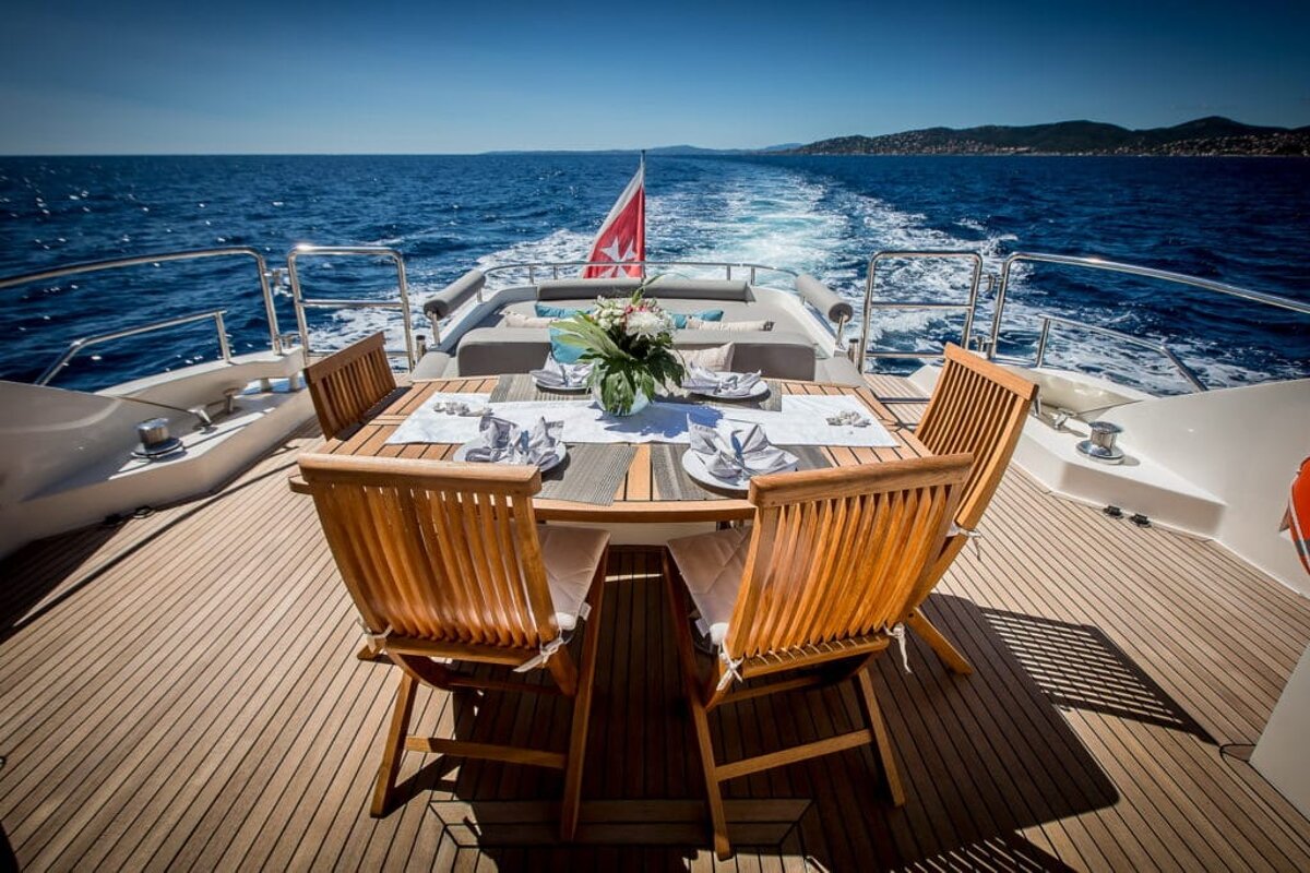 A table and chairs on the back of a boat in the ocean
