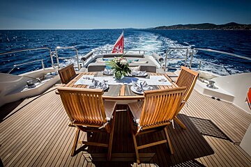 A table and chairs on the back of a boat in the ocean