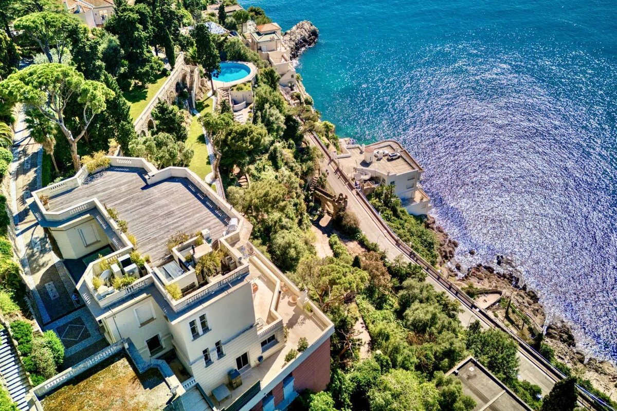 An aerial view of a house on a cliff overlooking the ocean