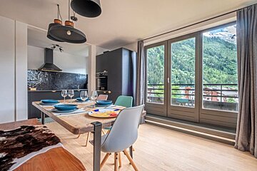 A dining room with a table and chairs and a view of the mountains