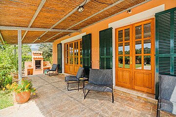 A patio with chairs and a table under a thatched roof