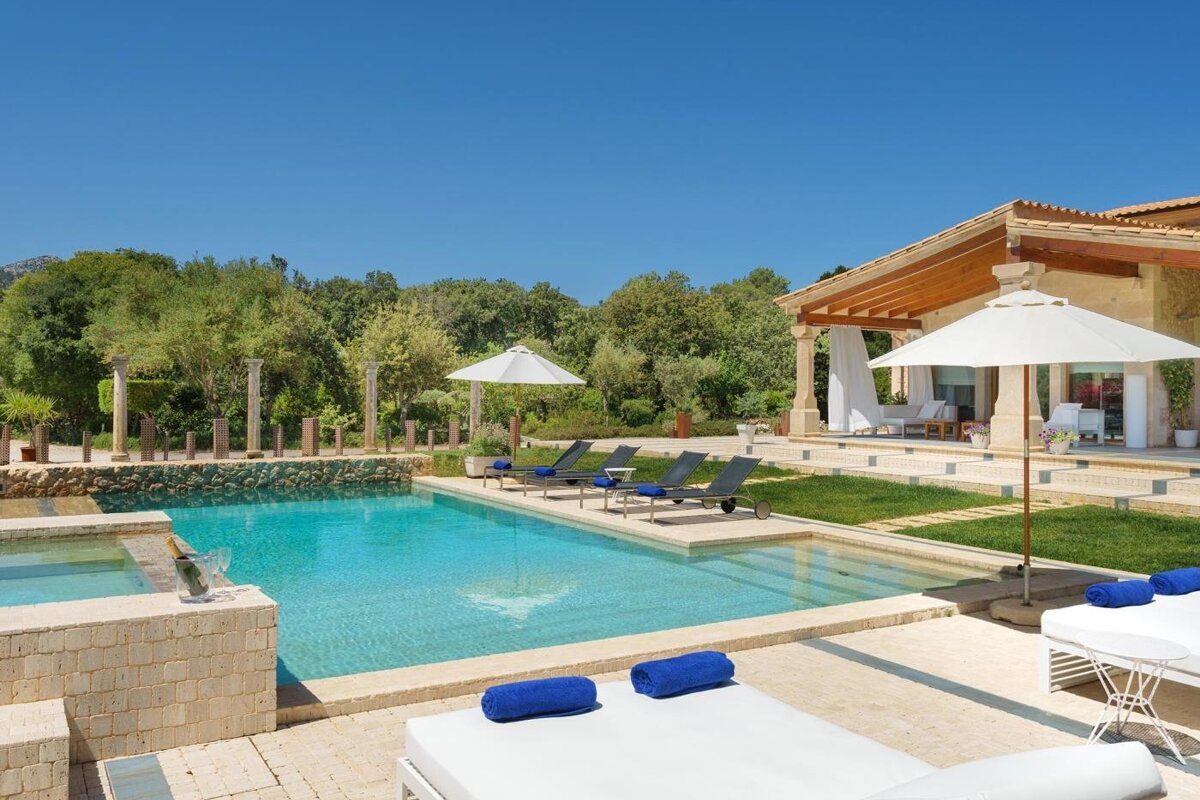 A large swimming pool is surrounded by lounge chairs and umbrellas