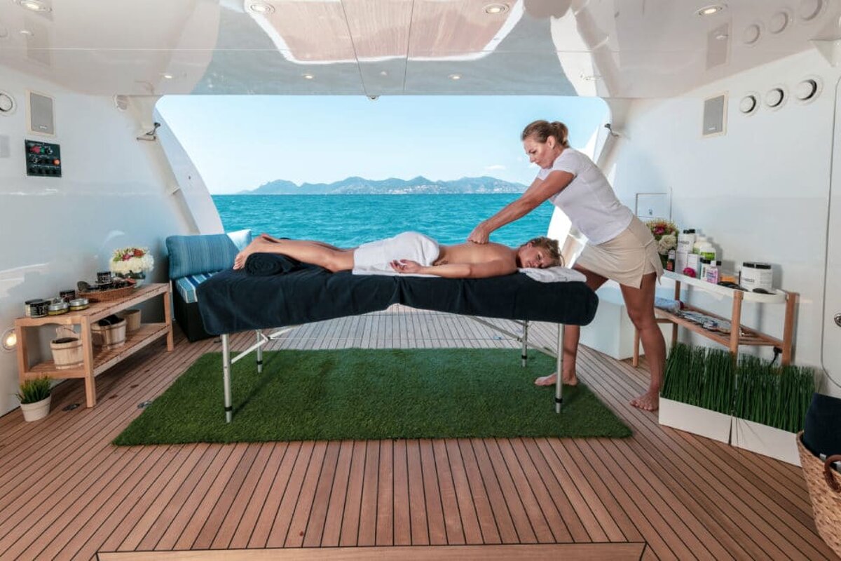 A woman is giving a man a massage on a boat