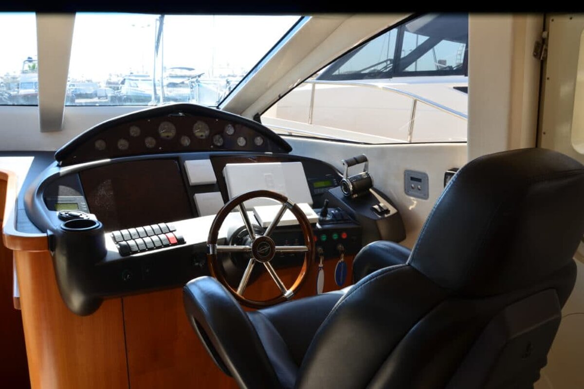 A steering wheel on a boat with a laptop on top of it