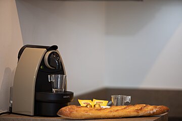 A krups coffee maker sits next to a loaf of bread