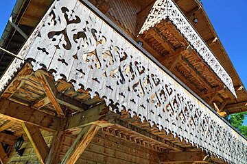 A wooden building with a balcony that has a fancy design on it